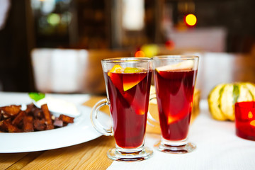 Two glasses of hot wine with fruit, rye croutons in white plate.