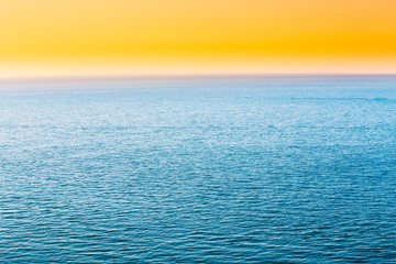 Obraz premium Blue Sea Or Ocean And Yellow Clear Sunset Or Sunrise Sky Background