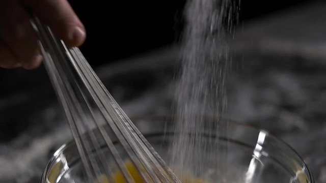 chef mixes the eggs with the sugar black background.