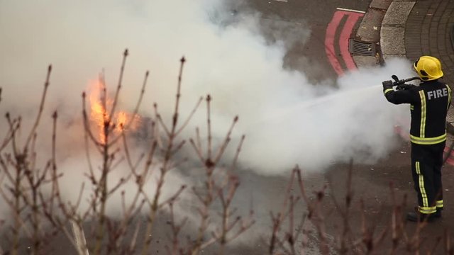 A telephoto shop showing fire fighters putting out a car fire following an accident
