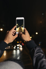 Boy takes a photograph of a street at night.