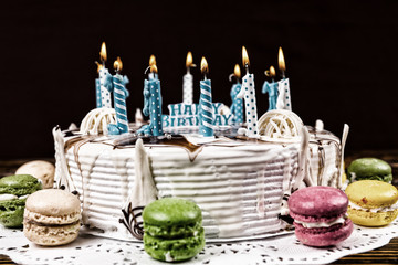 White appetizing birthday cake with lots of burning candles