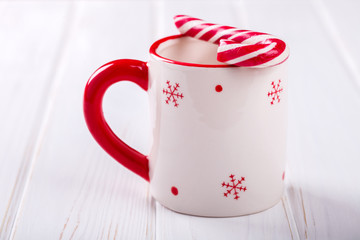 Obraz na płótnie Canvas White Christmas Cup with candy red Snowflake,Festive Drinks, on a White Background.selective focus.