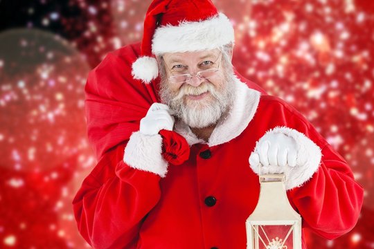 Composite image of santa claus holding christmas bag and lantern