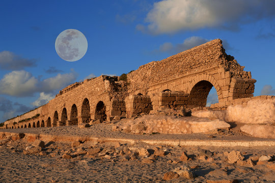 Aqueduct in Caesarea at sunset with a full moon