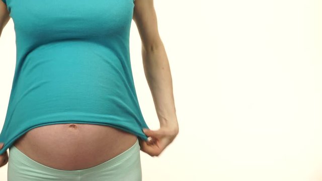Pregnant woman no face showing her big belly, closeup on white. Pregnancy, motherhood and baby anticipation concept. 4K ProRes HQ codec