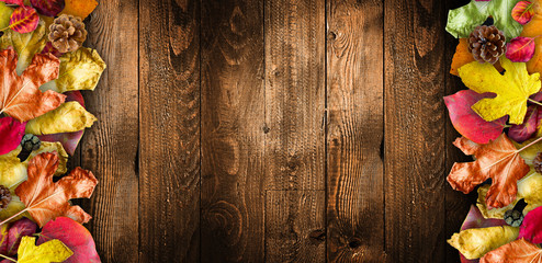 Autumn Leaves over a Natural Dark Wooden background. Old dirty wood tables or parquet with knots and holes and aged partculars.