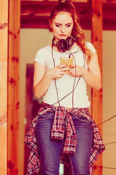 Woman with headphones choose music on smartphone.