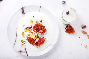 Yogurt in glass cups with nuts,pistachios and fresh figs.Breakfast,Dessert, Pudding on a white background.Food or Healthy diet concept.selective focus.Top view.