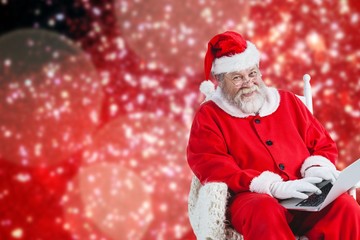 Composite image of portrait of cheerful santa claus typing on la