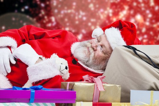 Composite image of close-up of tired santa claus sleeping beside