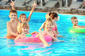 Fototapeta na wymiar Little kids in swimming pool on sunny day