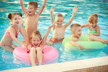 Fototapeta na wymiar Little kids in swimming pool on sunny day