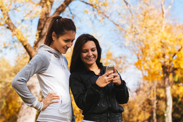 Girls in park, looking at mobile phone