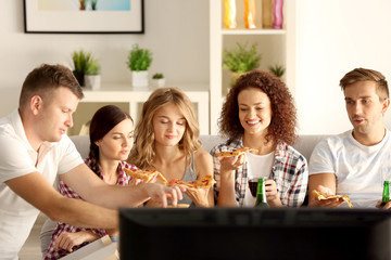 Friends eating pizza and watching TV at home party