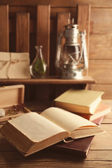 Fototapeta na wymiar Old books on table and home decor on shelf