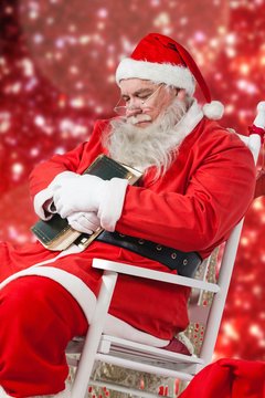 Composite image of santa claus holding bible while relaxing on c