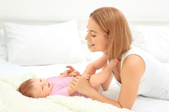 Young mother playing with her baby on bed