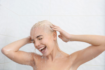 Beautiful young woman washing head in shower
