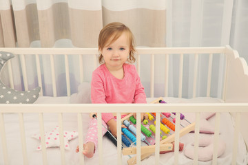 Cute little girl with toys in cradle at baby room