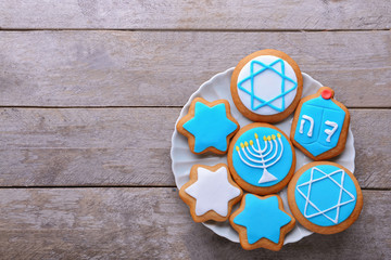 Plate with tasty cookies for Hanukkah on wooden table