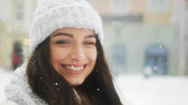 Attractive beautiful lady posing and flirting on camera over snowy city background