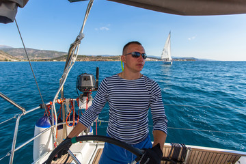 Skipper at the helm controls of a sailing yacht.