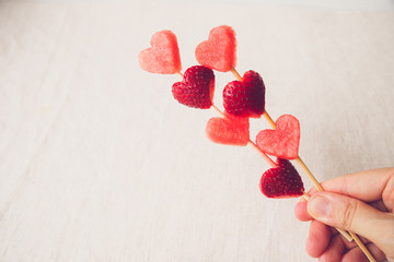 hand holding heart shape strawberry and watermelon fruit skewers
