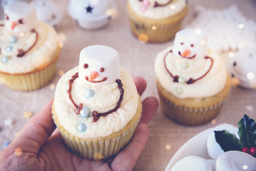 hand holding fun homemade melting snowman cupcakes for kids,toning