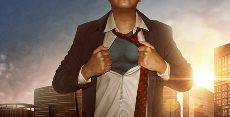 Businessman superhero in city building at sunset