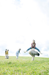 Fototapeta na wymiar 草原で馬跳びをする若者たち