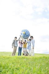 草原で地球のボールを持つ若者たち