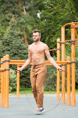 Fototapeta premium muscular sports man skipping rope outside