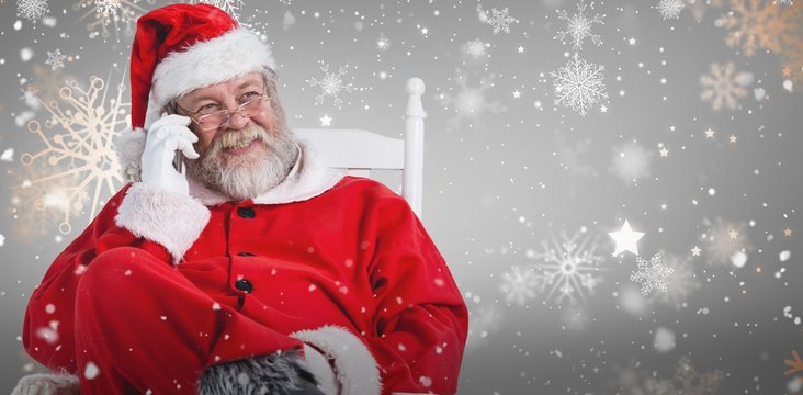 Composite image of santa claus using phone on chair