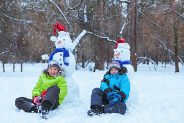 Fototapeta na wymiar fun, happy kids playing with snowman