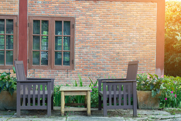 Fototapeta na wymiar Chair and table front home brick outdoor in garden. Soft flare sunlight.