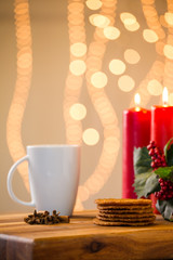 Lovely close up image of Christmas cookies on a wooden chopping board with some scented candles and a glass of whiskey / coffee and some cinnamon sticks.