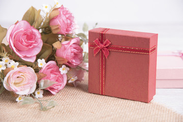 Vintage red gift box and pink rose flower on wooden background for christmas and new year.