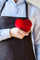 Servicing man in apron holding heart - customer relationship and service minded business concept