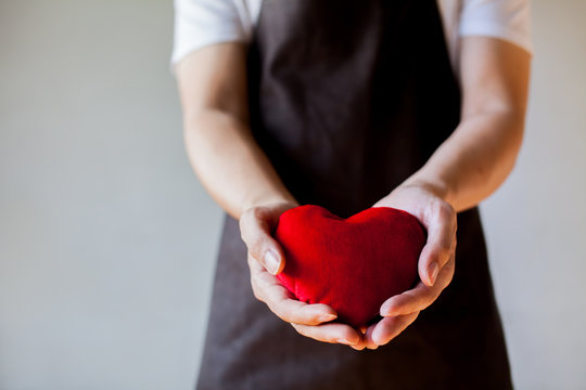 Servicing man in apron holding heart - customer relationship and service minded business concept