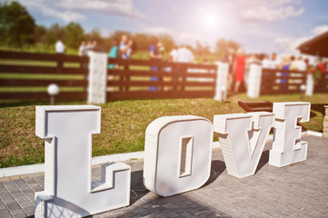Big word LOVE on wedding ceremony background guests.