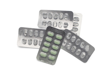 Green pill in package on pile of empty pills packages from top view isolated on white background