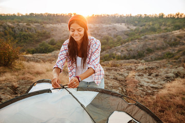 Young happy caucasian woman setting up a tent outdoors - Powered by Adobe