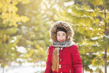 Portrait of little girl in red jacket smiles in park in winter