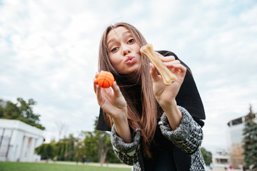 Cute woman playing with small ball and bone outdoors