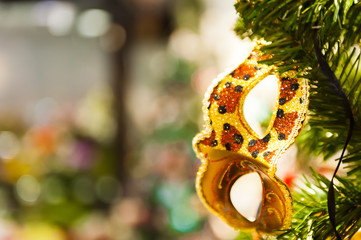 Beautiful carnival mask hanging on the Christmas tree in the background of bright blurred...