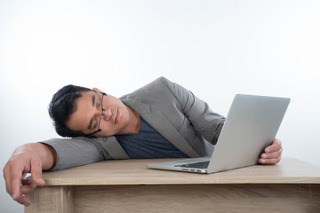Young man sleeps on a workplace with a laptop computer