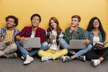 Multiethnic group of happy friends with laptops sitting and smiling
