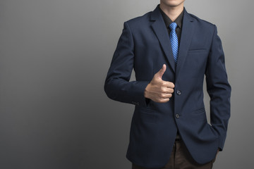 Close up of businessman in blue suit thumbs up on gray backgroun
