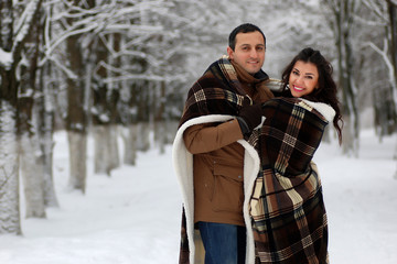Fototapeta na wymiar beautiful young couple in a snowy park wrapped